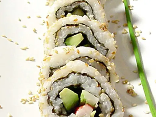 En närbild på en california roll med avokado och krabba, strödd med sesamfrön.