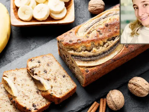 Un delicioso banana bread casero, con trozos de chocolate y plátano en rodajas, junto a nueces y canela.