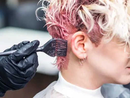 Aplicando tinte rosa en el cabello. Si te manchas, aprende como quitar el tinte de la piel.