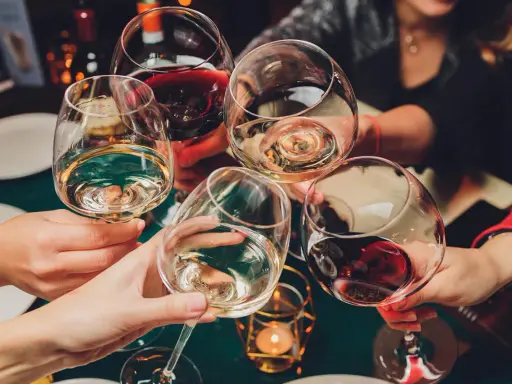 Ludzie wznoszą toasty winem. Pamiętaj o odpowiedzialnym spożywaniu alkoholu, zwłaszcza gdy rozważasz antykoncepcję.