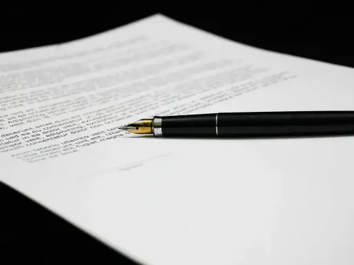 Una penna stilografica nera su un foglio di testo, forse una lettera di richiamo per assenza ingiustificata.