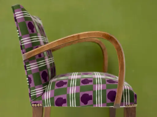Fauteuil au motif écossais violet et vert, avec des silhouettes de têtes. Un bel exemple d'art tapissier.