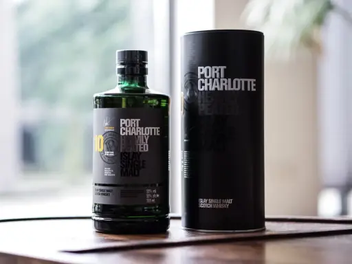 Port Charlotte Heavily Peated 10, whisky single malt z Islay, w zielonej butelce i czarnej tubie.