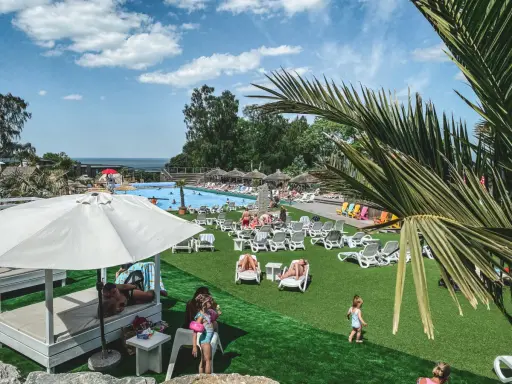Solig dag vid poolen, perfekt för en semester i Sverige med barn. Folk solar, badar och njuter av värmen.
