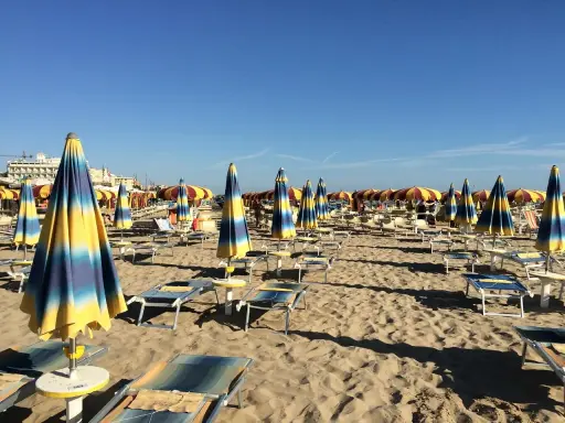 Ombrelloni a righe blu e gialle e lettini vuoti sulla spiaggia di Rivazzurra, in attesa dei bagnanti.