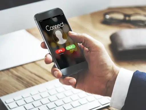 Dłoń trzyma smartfon z ekranem połączenia. Dowiedz się, jak odsłuchać pocztę głosową plus, gdy dzwoni telefon.
