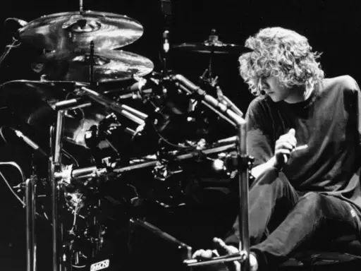 Def Leppard trummis Rick Allen sitter vid sitt trumset, redo att leverera en kraftfull rytm.