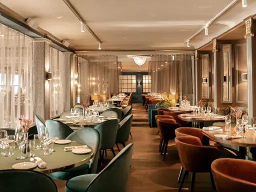Elegant dining room at Hasselbacken restaurang, Stockholm. Tables set with glassware and cutlery, plush seating, and soft lighting create a sophisticated atmosphere.