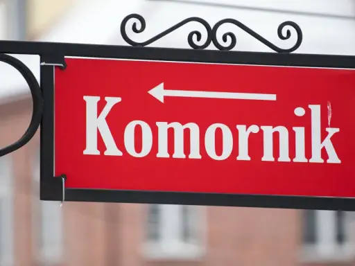 Tabliczka "Komornik" z białą strzałką w lewo. Zastanawiasz się, ile komornik może zabrać z emerytury?