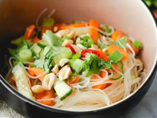 Frischer Glasnudel Salat mit Karotten, Gurken, Frühlingszwiebeln und Erdnüssen in einer Schüssel.