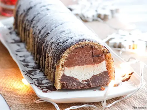 Bûche glacée chocolat, vanille et chocolat, saupoudrée de sucre glace. Une délicieuse recette pour les fêtes.