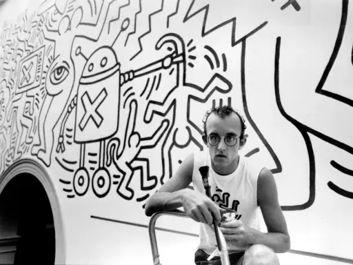 Keith Haring, a pioneer of queer art, poses with his iconic figures in this black and white image.