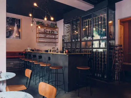 Mysig vinbar i Stockholm med en stor vinkyl, bardisk och sittplatser.