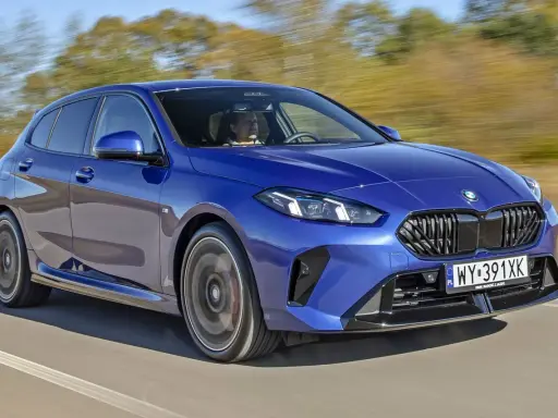 Niebieskie BMW serii 1 (f21) w ruchu, z kierowcą za kierownicą.