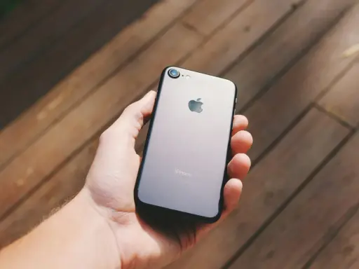 Dłoń trzyma szarego iPhone'a. Chcesz wiedzieć, jak sprawdzić, czy iPhone jest oryginalny? Zwróć uwagę na detale.