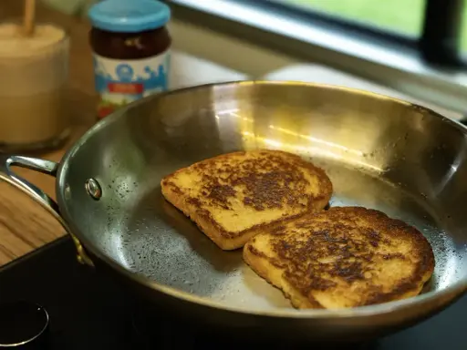 Dos tostadas francesas dorándose en una sartén de acero inoxidable, mostrando las ventajas e inconvenientes de este material para cocinar.