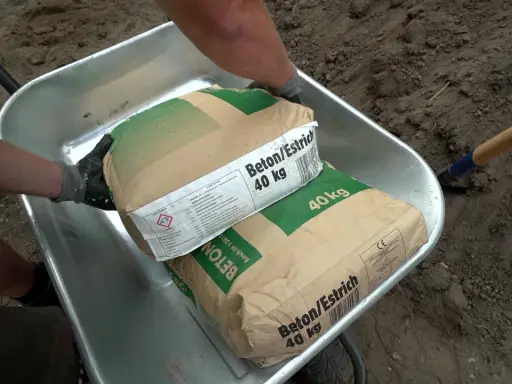 Zwei Säcke Beton/Estrich 40 kg liegen in einer Schubkarre. Verschiedene Estrich Arten sind für Bauprojekte wichtig.