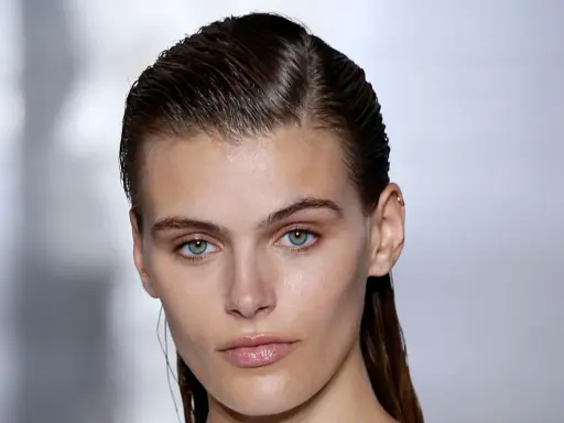 Ein Model mit glänzenden, nassen Haaren im Wet-Look-Stil, das einen intensiven Blick in die Kamera wirft.