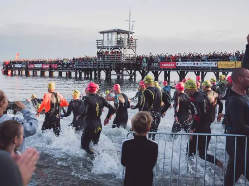 Triathleten starten ins Wasser, die Menge jubelt vom Steg. Die Ironman Vorbereitung ist in vollem Gange.