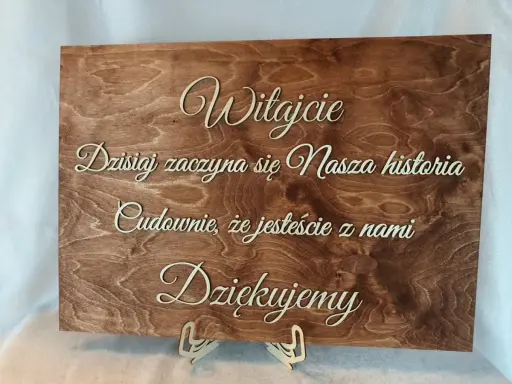 Drewniana tablica powitalna ślub: "Witajcie! Dzisiaj zaczyna się Nasza historia. Cudownie, że jesteście z nami. Dziękujemy.