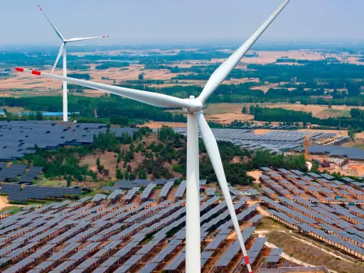 Große Windturbinen und weite Felder von Solarmodulen zeigen Chinas Engagement für erneuerbare Energien.