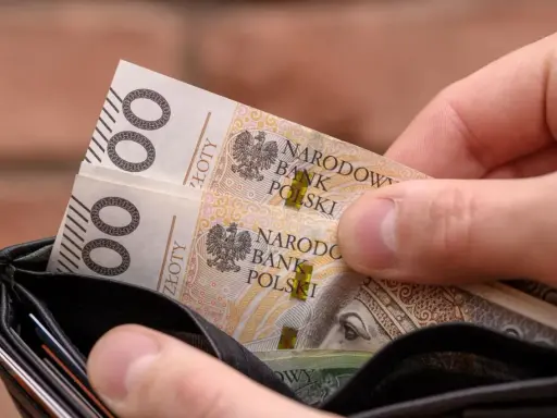 Dłoń wkłada do portfela banknoty 100 zł. Czy to na bieżące wydatki, czy może na 13. emeryturę?
