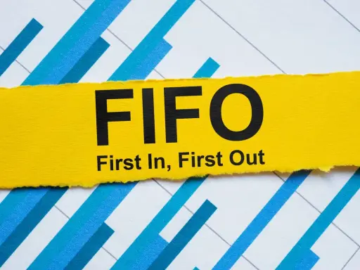 Żółty pasek z napisem FIFO (First In, First Out) na tle wykresu. Zasada fifo lifo w zarządzaniu zapasami.