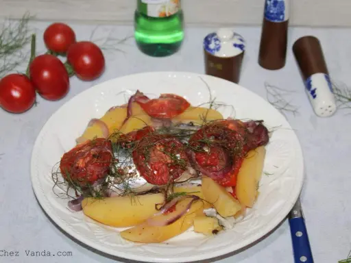Maquereau au vin blanc, pommes de terre, tomates et oignons sur une assiette blanche.
