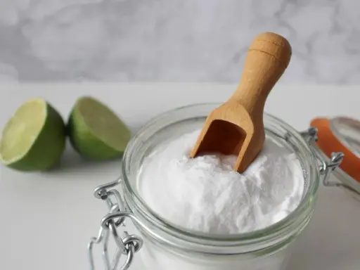 Bicarbonato e lime, ingredienti naturali per combattere la forfora. Un cucchiaino di bicarbonato in un barattolo di vetro.