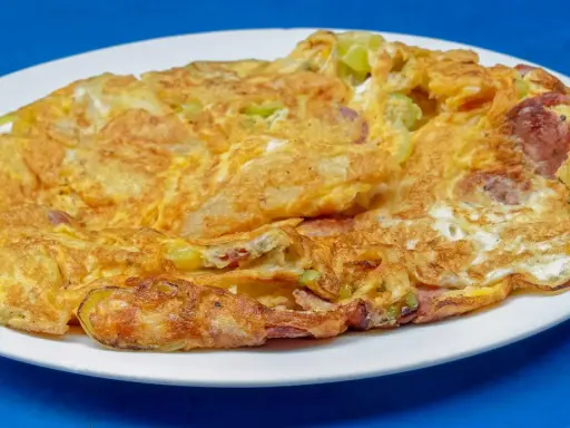 Złocisty omlet z warzywami i kawałkami kiełbasy, idealny przykład, jak się robi omlet dietetyczny.
