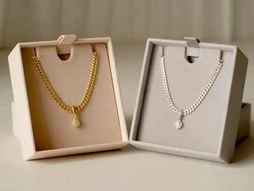Due collane, una in oro e una in argento, con pendente scintillante, presentate in eleganti scatole.
