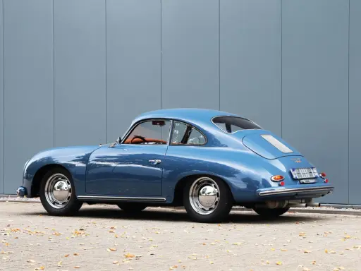 Blauer Porsche 1600 Super Coupé, ein Klassiker mit hohem Wert, steht vor einer grauen Wand.