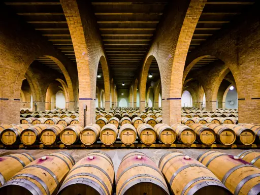 Bodegas subterráneas con hileras de barricas de vino, evocando la tradición del Camino de Santiago. Una fuente de vino para peregrinos.