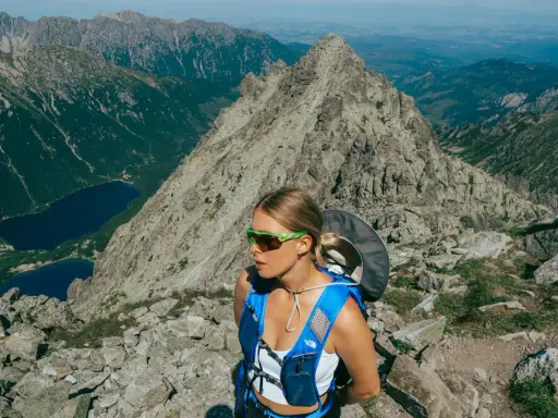 Kobieta w okularach i niebieskim plecaku na tle górskich krajobrazów. Beskid Śląski oferuje takie widoki i atrakcje.