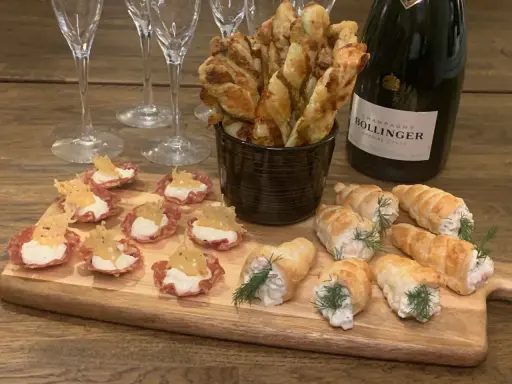 En flaska Bollinger och en bricka med läckra tilltugg till bubbel: små salta korgar, smördegsrullar och ostpinnar.