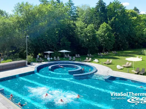 Außenpool der VitaSol Therme Bad Salzuflen mit Liegen und Bäumen.