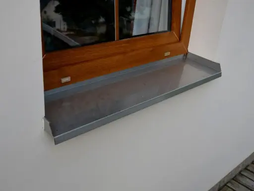 Szary parapet zewnętrzny plastikowy pod drewnianym oknem.