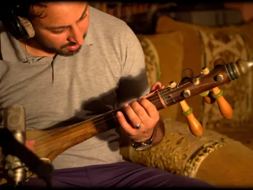 Un homme joue d'un instrument à corde marocain, un guembri, devant un microphone.