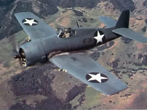 F6F Hellcat fliegt über hügelige Landschaft.