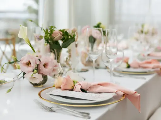 En vacker fest dukning med rosa blommor, glas och menyer.