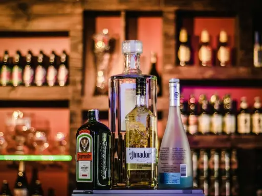 Butelki alkoholi na półce barowej: Jägermeister, tequila El Jimador, Absolut i Hypnotiq. Czy wiesz, whisky ile procent ma?
