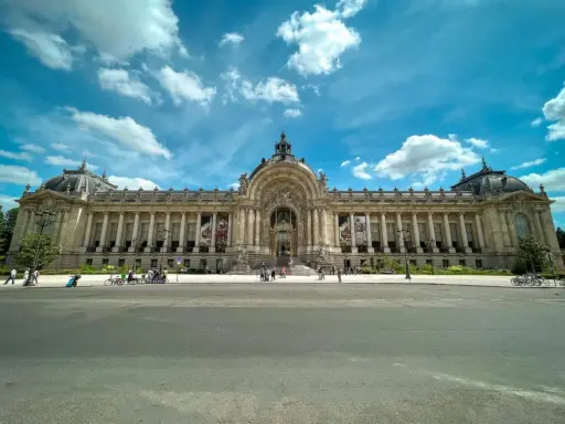 Grand Palais w Paryżu, jeden z najważniejszych zabytków Paryża, z kolumnadą i kopułą pod błękitnym niebem.