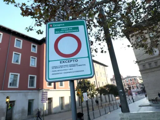 Señal de etiqueta medioambiental en Zaragoza, indicando zona de bajas emisiones con excepciones para carga, descarga, taxis, bicicletas y residentes.