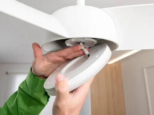 Manos conectando cables para como instalar un ventilador de techo con luz.