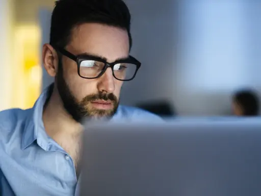 Uomo con occhiali studia al computer, concentrato su un corso di paghe e contributi.