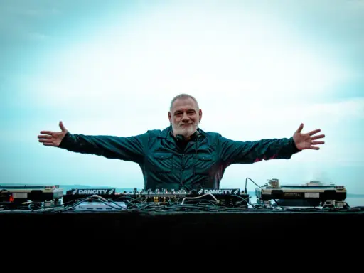 DJ Ralf, un vero patrimonio della musica elettronica, con le braccia aperte davanti alla sua consolle, pronto a far ballare il mondo.