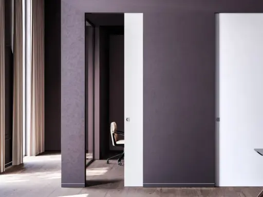 Paredes blancas y puertas de color blanco y morado oscuro, con una silla de oficina y un escritorio.