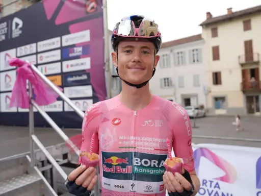 Radfahrer des Teams Red Bull Bora Hansgrohe hält einen Muffin mit Kerze.