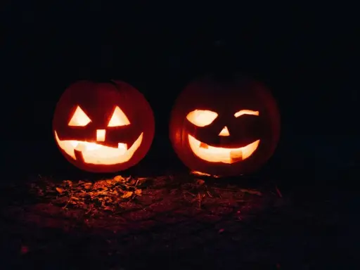 Två lysande pumpor med läskiga ansikten lyser upp mörkret. En perfekt syn för en halloween dag.