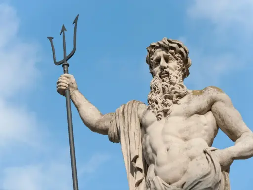 Statue de Poseidon dieu des mers, tenant son trident, sous un ciel bleu.